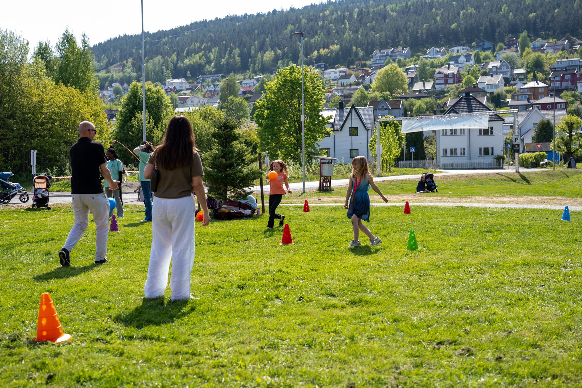 To voksne og to barn leker med ball. Kjegler er satt opp som bane.
