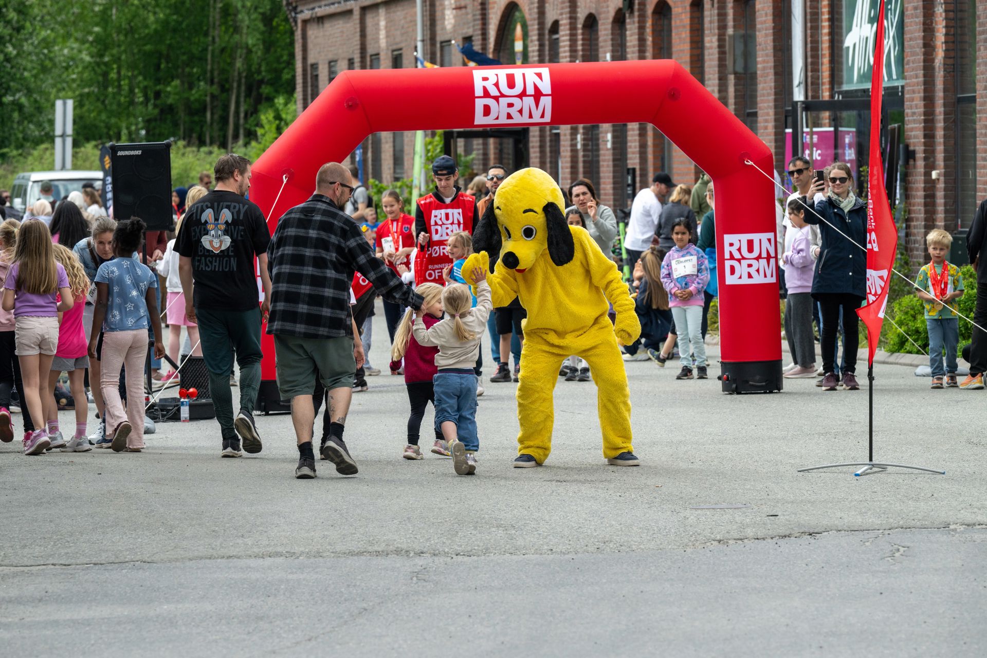 Gul maskot står sammen med barna på startstreken til løpet.