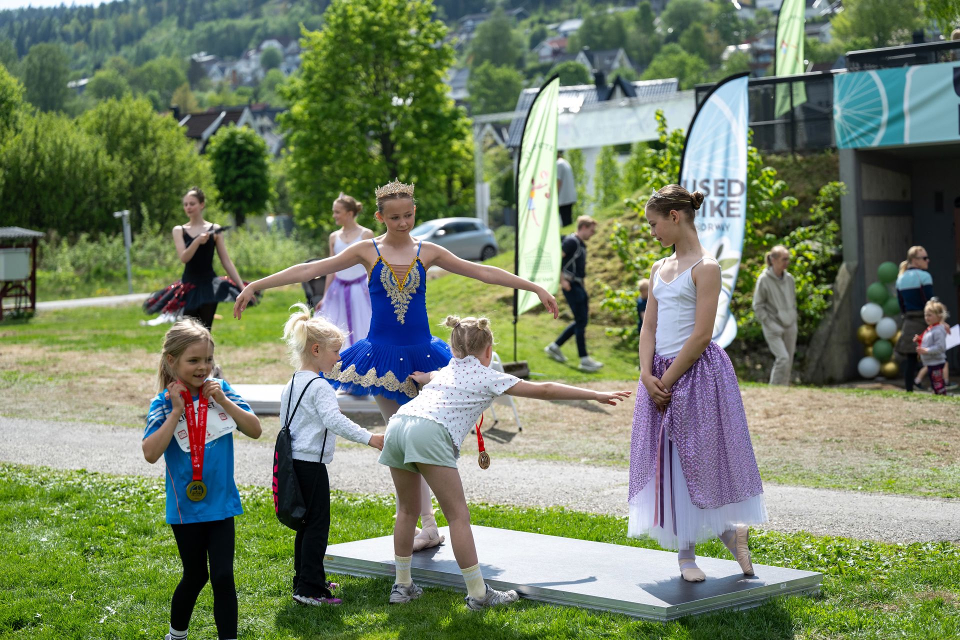 To ballettdansere viser frem trinn til noen barn.