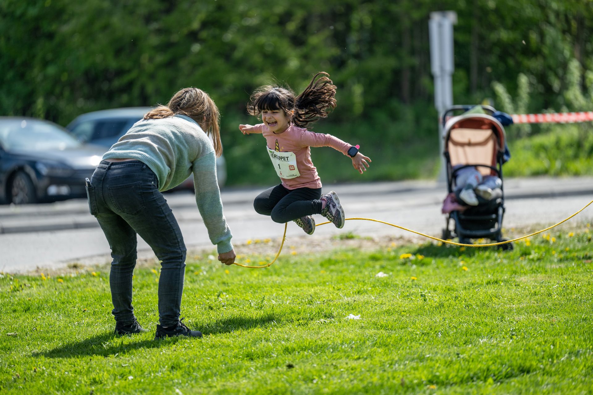 En jente med pannelugg hopper slengtau med et stort smil om munnen. 